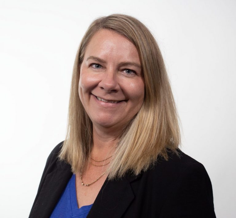 Head and shoulders photo of a woman in a blue shirt and a black jacket.